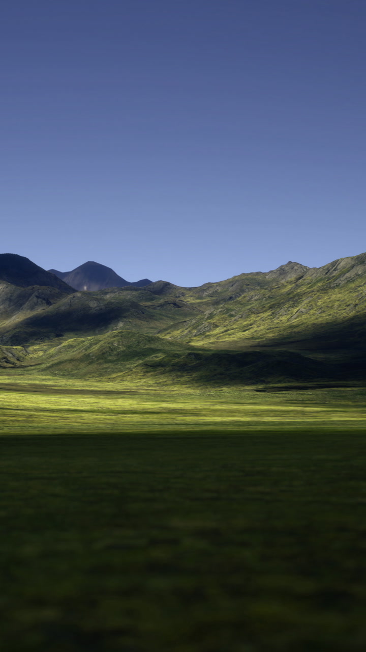 Vibrant green meadows stretch across the valley under a clear blue sky