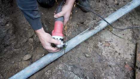 worker cutting tube with angle grinder