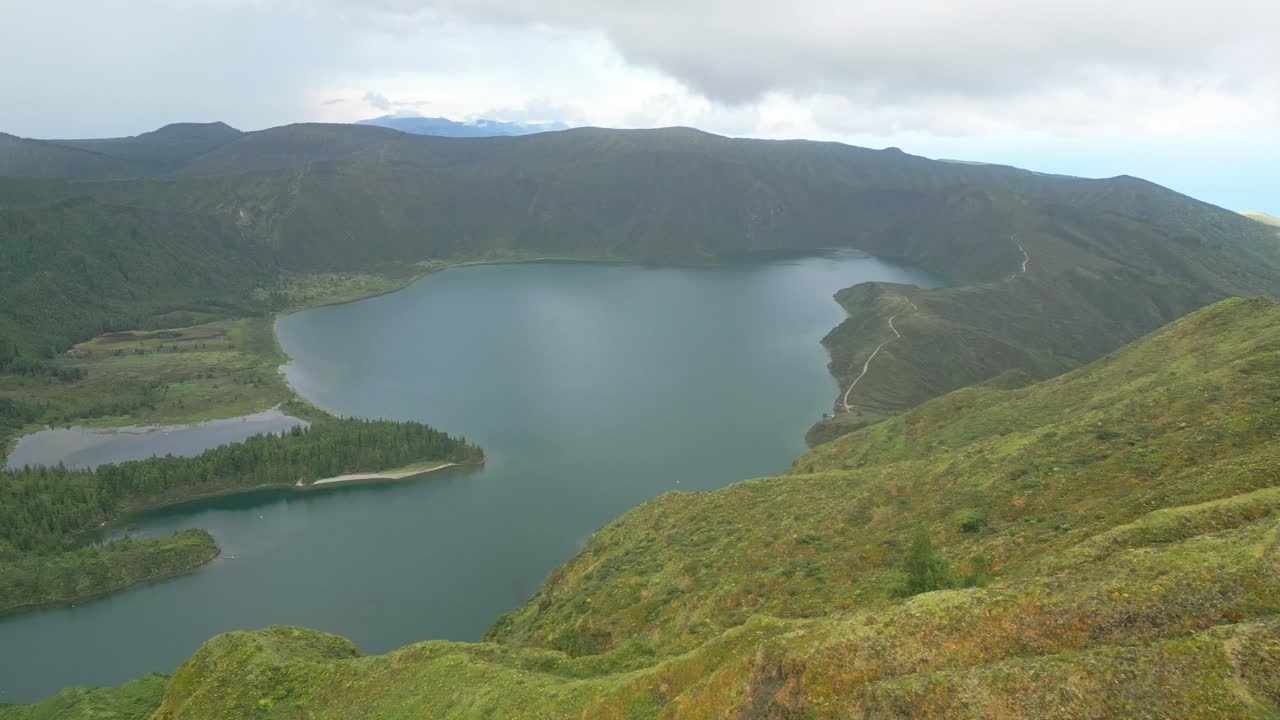 푸른 산과 구름이 가득한 하늘로 둘러싸인 lagoa do fogo 호수