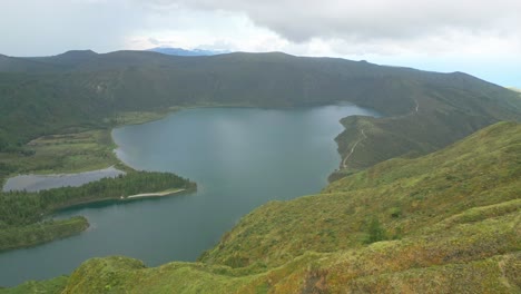 el lago lagoa do fogo rodeado de exuberantes montañas verdes y un cielo nublado