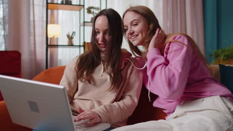 una pareja de mujeres jóvenes adultas mirando la pantalla de un portátil haciendo compras en línea en casa