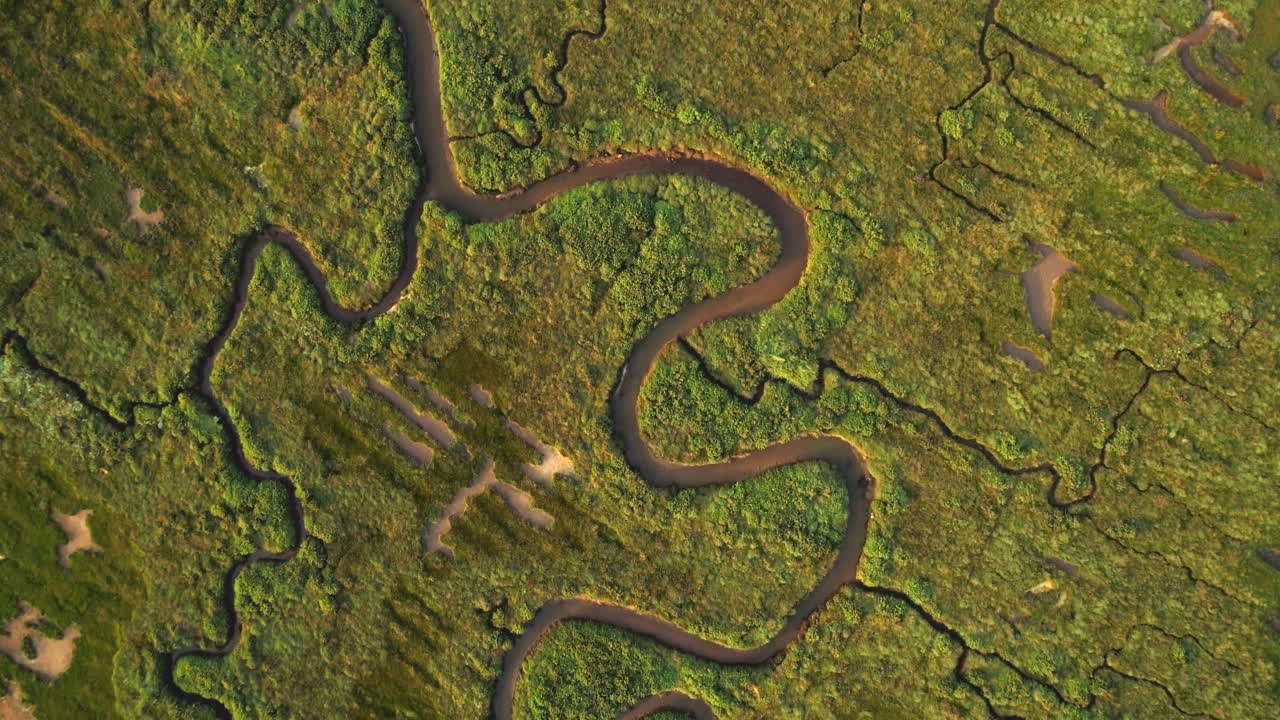 un dron abstracto de arriba hacia abajo disparó sobre una marisma salada verde con un canal sinuoso en la costa este del reino unido de north norfolk