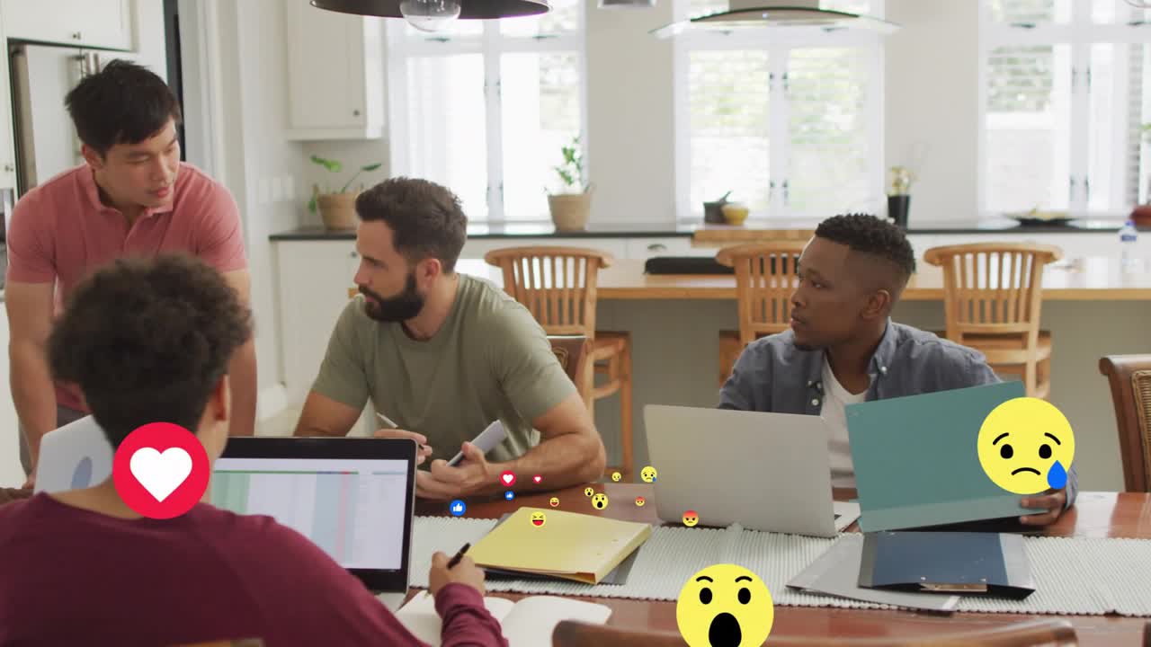 Standing man leaning on table addressing team creating floating reaction icons in office meeting