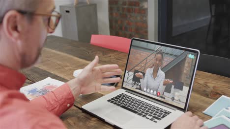 hombre de negocios caucásico en una llamada de video portátil con una colega afroamericana en la pantalla