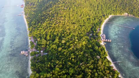 vista aérea de la selva tropical cubierta de bosque tropical paisaje de la isla con cabañas en la playa frente al mar en raja ampat, papúa occidental, indonesia