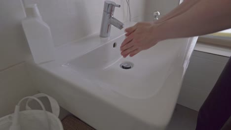 person washing hands in bathroom sink