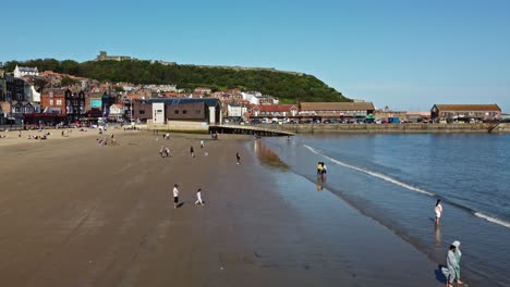 Vista-Aérea-De-La-Playa-Durante-El-Verano-Revelando-Cielo-Azul-Y-Mar-En-Calma-Scarborough-Inglaterra