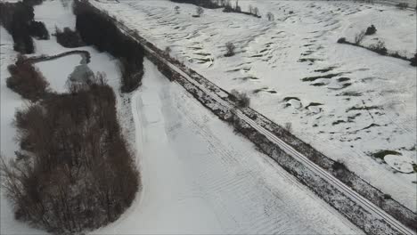 aerial flyover of a golf course covered in snow with railway train tracks