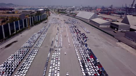 Aerial-view-of-logistics-concept-of-commercial-vehicles,-cars-and-pickup-trucks-waiting-to-be-load-on-to-a-roll-on-roll-off-car-carrier-ship