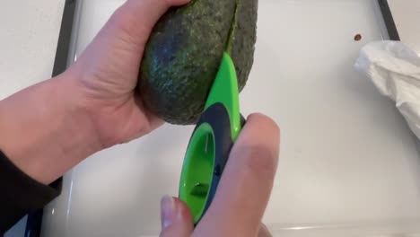 using an avocado cutter to slice open an avocado in half