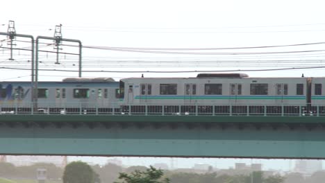 jr train passing by on the marukobashi bridge over the tamagawa river at dusk in tokyo, japan
