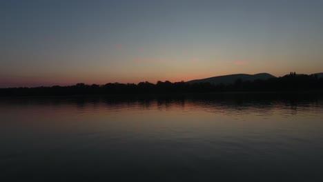 flying over water towards sunset, or sunrise over the mountains