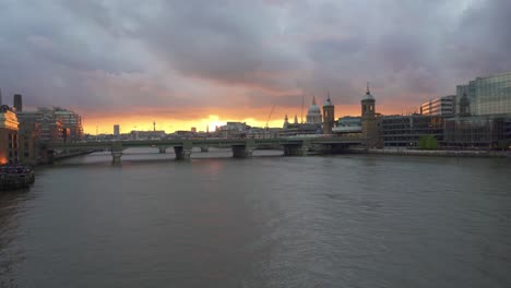 panning shot from london bridge looking over the river thames at the iconic monuments of the city of london including st pauls cathedral and blackfriars station bridge at sunset