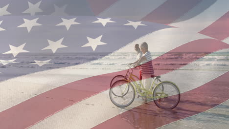 animation of flag of united states of america over happy senior couple with bikes on beach by sea