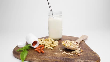 Cutting-board-with-cashews-and-pills-with-cereals-for-a-beautiful-breakfast-against-white-background