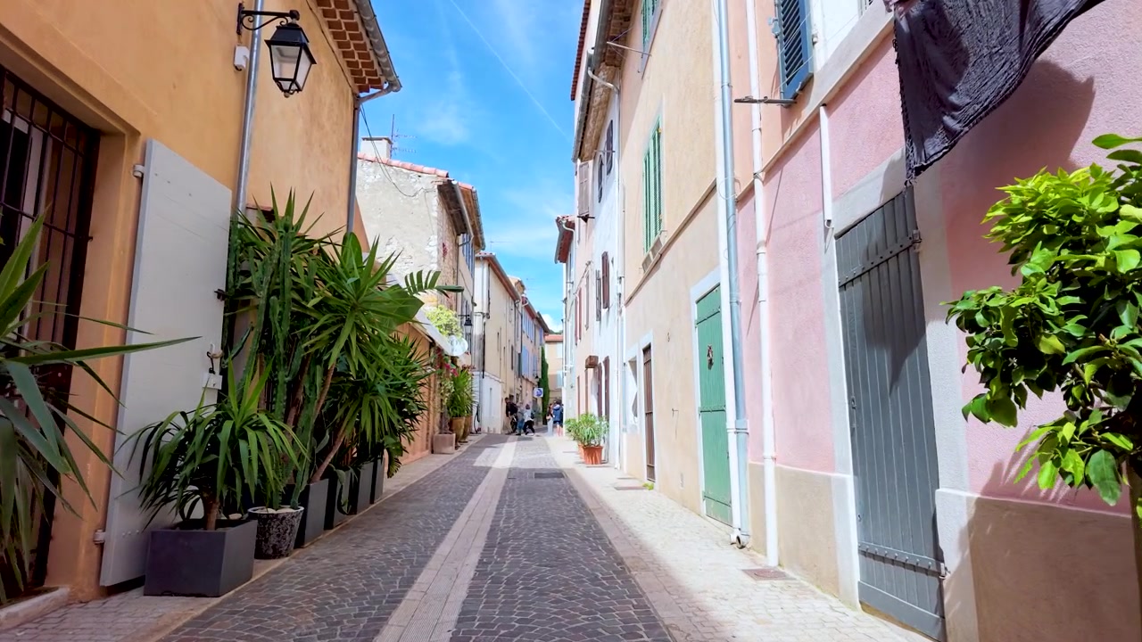 Una lenta carrellata in avanti attraverso un affascinante vicolo stretto con edifici colorati e vegetazione.