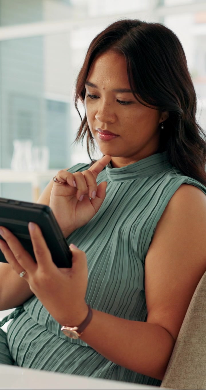 Fokuseret kvinde bruger digital tablet på et moderne kontor.