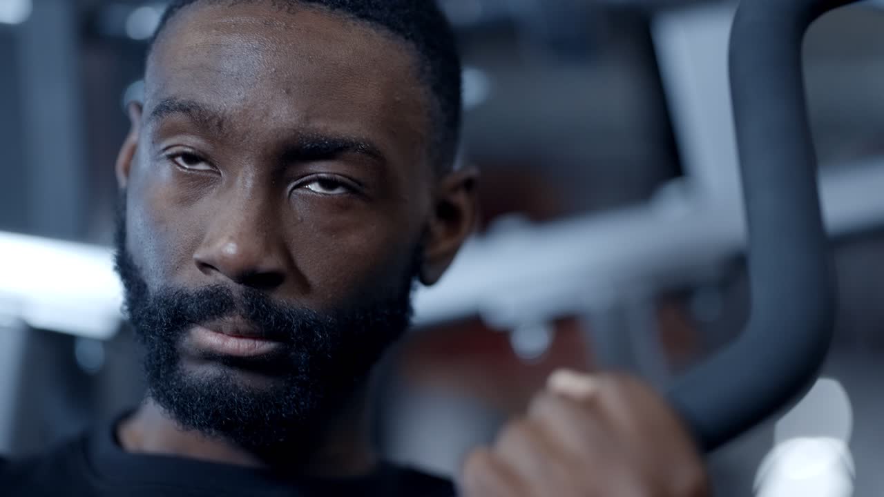 An african american athletic man performs lat pull downs