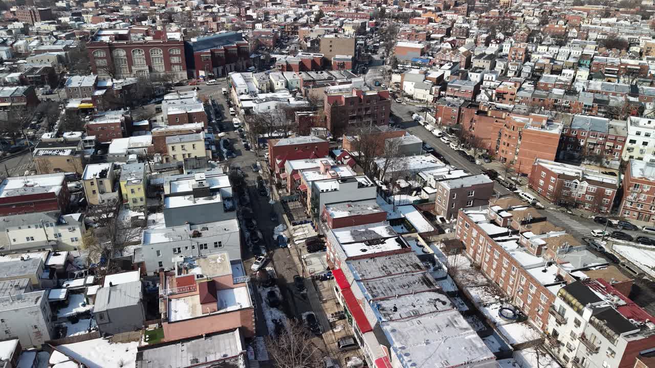 Luftaufnahme aus der Vogelperspektive über einem dicht besiedelten Stadtgebiet in den USA, die schneebedeckte Dächer, Wohngebäude und ruhige Straßen an einem sonnigen Wintertag zeigt.