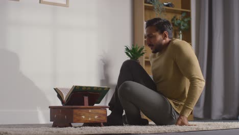 muslim man at home sitting and reciting from the quran