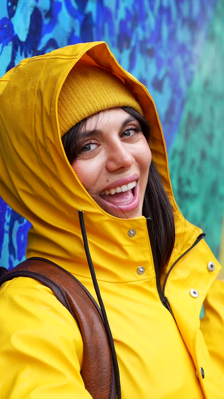Giovane donna felice con impermeabile giallo che sorride all'aperto