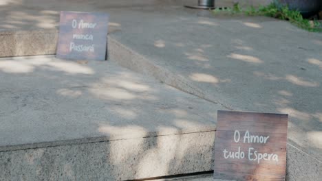 two wooden signs with love quotes placed on outdoor steps in a shaded area.