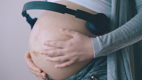 pregnant lady with headphones on tummy dances in room