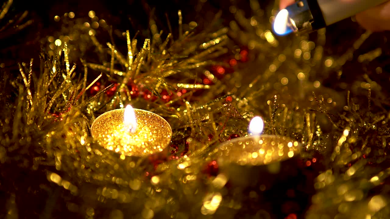 Mano che accende le luci della decorazione natalizia, con candele dorate.