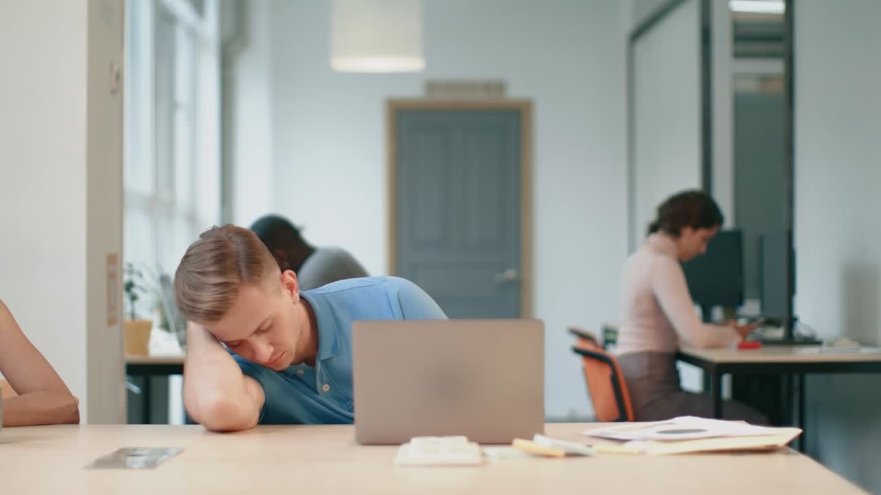Forretningsmann sover på felleskontor. Profesjonell gir kaffe til sliten kollega.