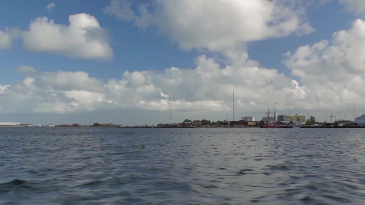 Floating along the sea from right to left in a sunny day with cloudy sky. View of the waterfront of Copenhagen, Denmark.
