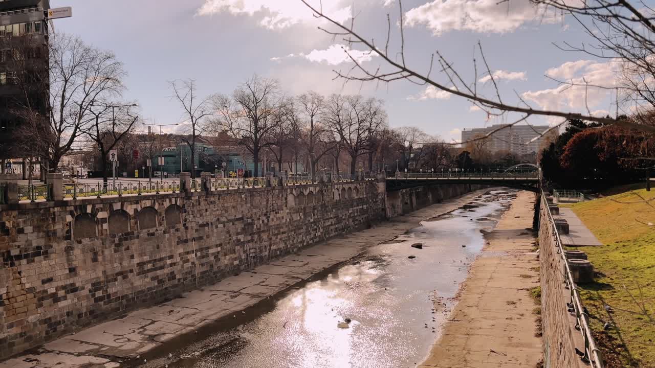 shallow urban river canal with stone embankments and a dry riverbed in Vienna, Austria