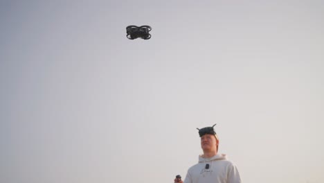 low angle view of drone hover in air and guy with fpv goggles, empty sky behind