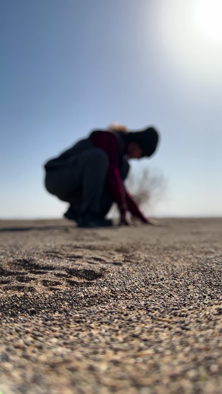 slow motion of hot weathet desert golden sand woman sitting in warm sunlight touch fine particles golden landscape summer travel vacation iran nature ambient scene relaxation wanderlust dry land