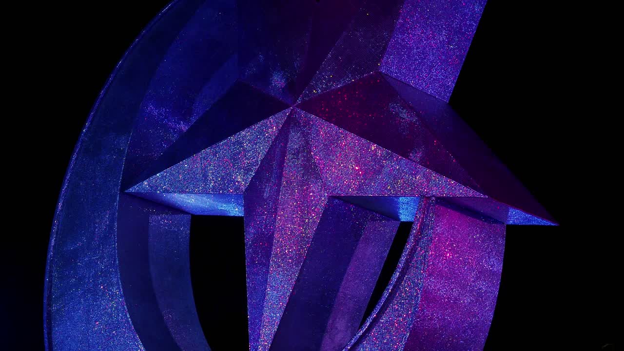 Low angle of glittery star and crescent statue lit by colorful lights at night