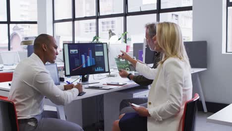 diversas personas de negocios sentadas usando computadora y hablando en el escritorio en la oficina