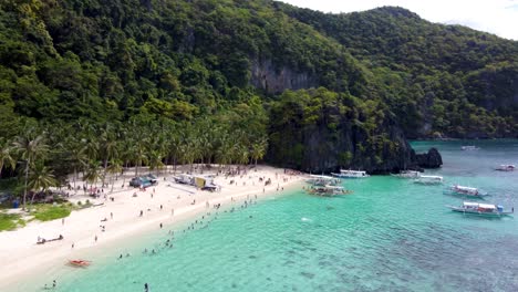 tour boats departing and arriving tropical seven commando beach in el nido unloading tourists swimming in aquamarine clear water