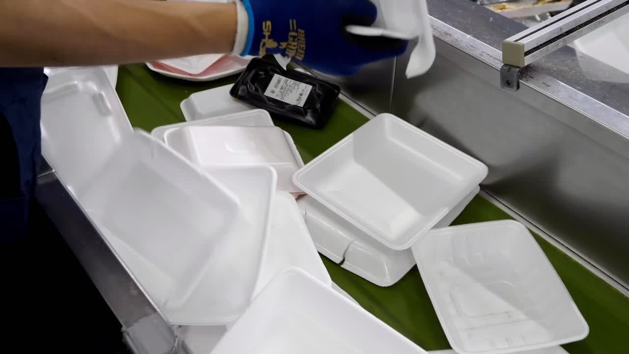 Workers carefully separate boxes, foam, and paper packaging as they move along conveyor belts.