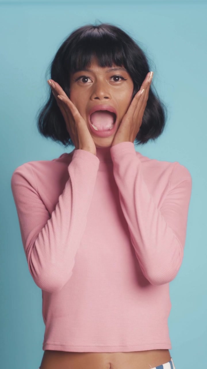 Surprised southeast asian woman shouting and holding cheeks with shocked facial