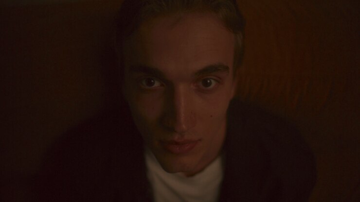 Portrait of Young Man Leaning Back on Sofa and Looking into Camera