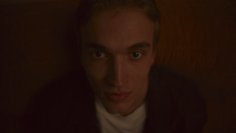 portrait of young man leaning back on sofa and looking into camera