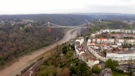 an aerial shot flying towards the clifton suspension bridge and the city of bristol from on a cloudy day