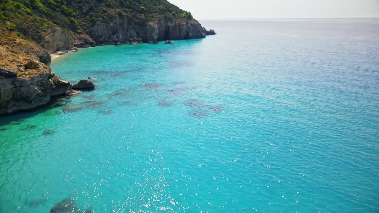 Vista aerea da drone di un uomo che galleggia su una barca vicino alla costa di Zante, Grecia. Acqua blu e trasparente del Mar Ionio