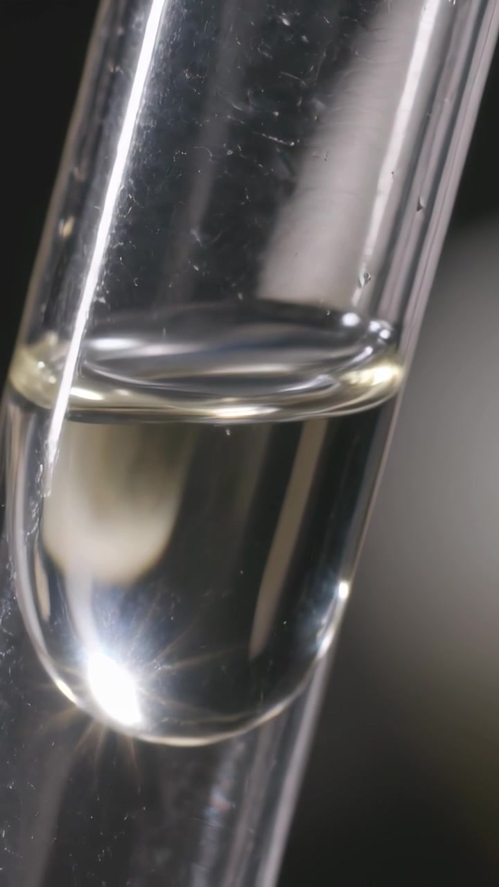 Vertical video: Moving light causing glass tube meniscus relaxing and hanging drop adjusting in lab
