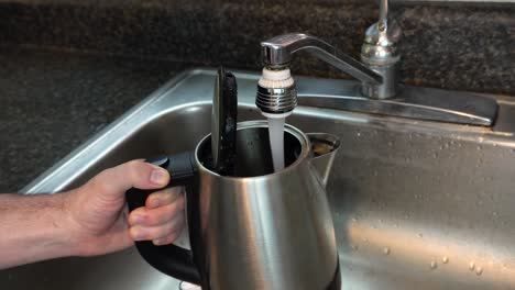 take of someone filling up a hot drink kettle for making tea or coffee