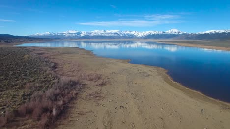 A-beautiful-aerial-over-a-mountain-lake-reveals-the-Sierra-Nevada-mountains-in-winter-with-plentiful-water