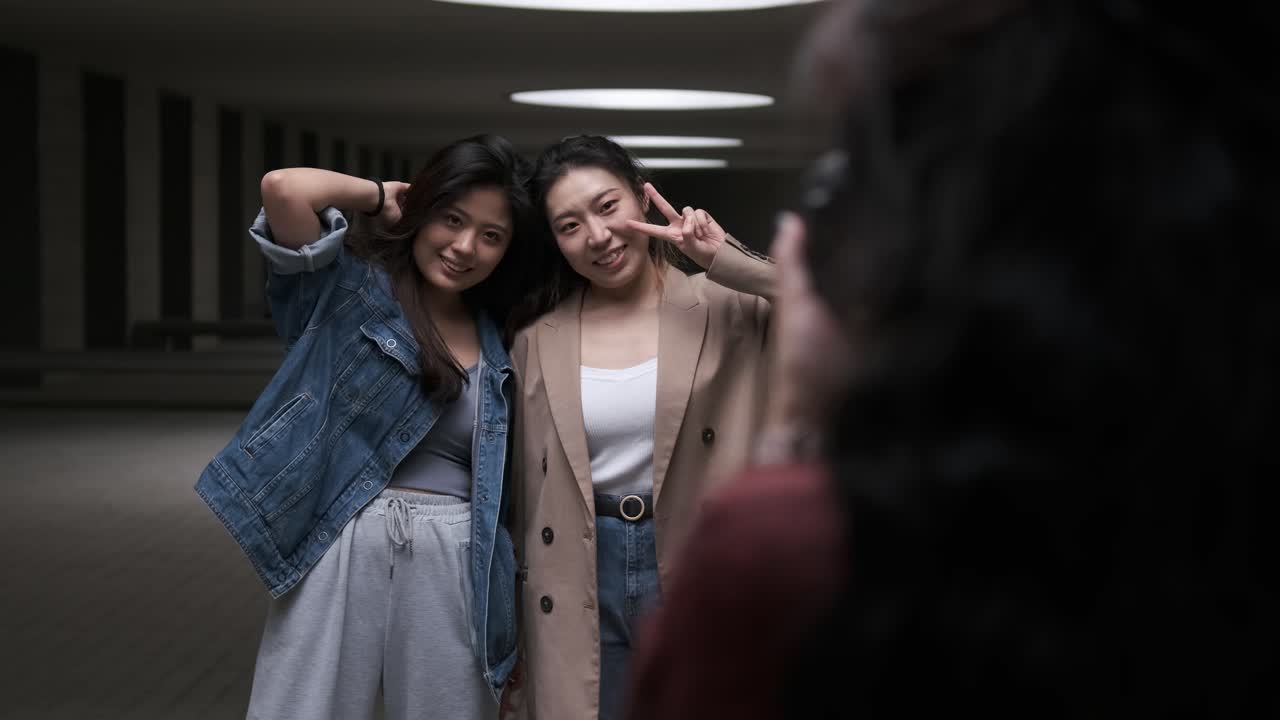 Two young asian women posing to the camera while the photographer taking some photos