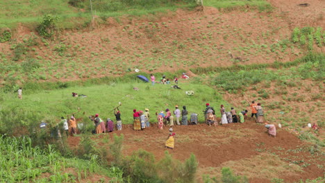 wide shot of a group of people plowing a hillside in rural rwanda