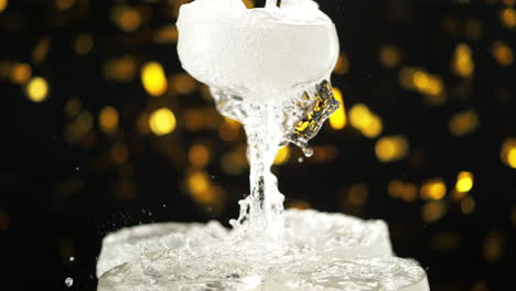 champagne is poured into the top glass of the tower, overflows and cascades down in slow motion, golden confetti falls in slow motion