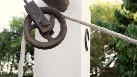 closeup of the pulley wheel used to draw water from the well in a bucked tied to a rope