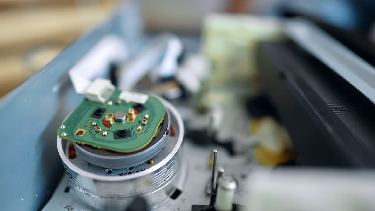 VHS tape enters the DVD player. Reels moving as reading the content of the record. Extreme close up